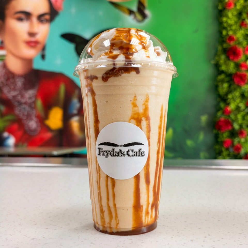 Caramel-drizzled whipped cream frappé in an Eydas Cafe cup, displayed against a colorful floral and butterfly mural.